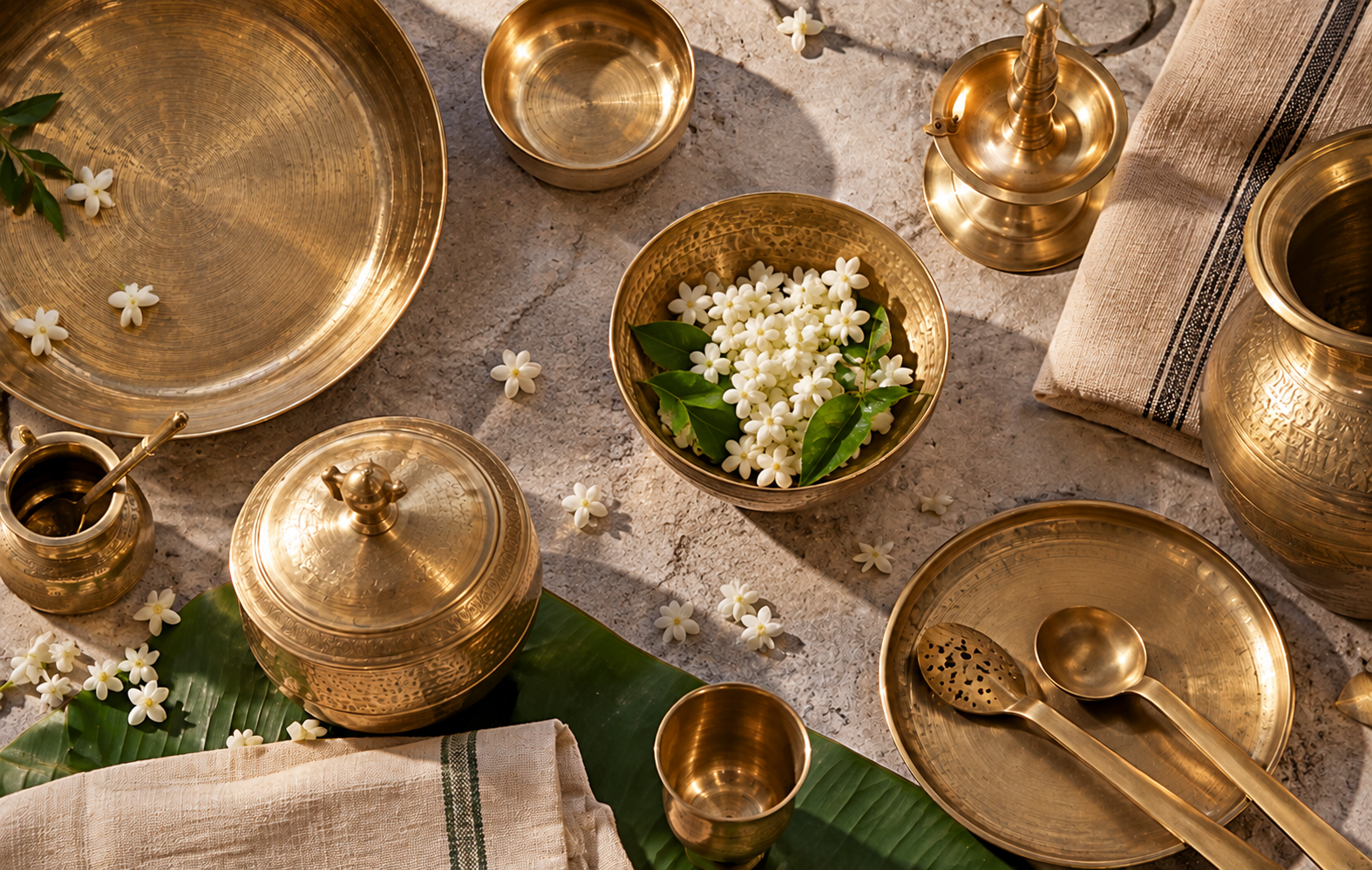 Handcrafted Kerala bell metal tableware, ceremonial vessels, and jasmine floral arrangements
